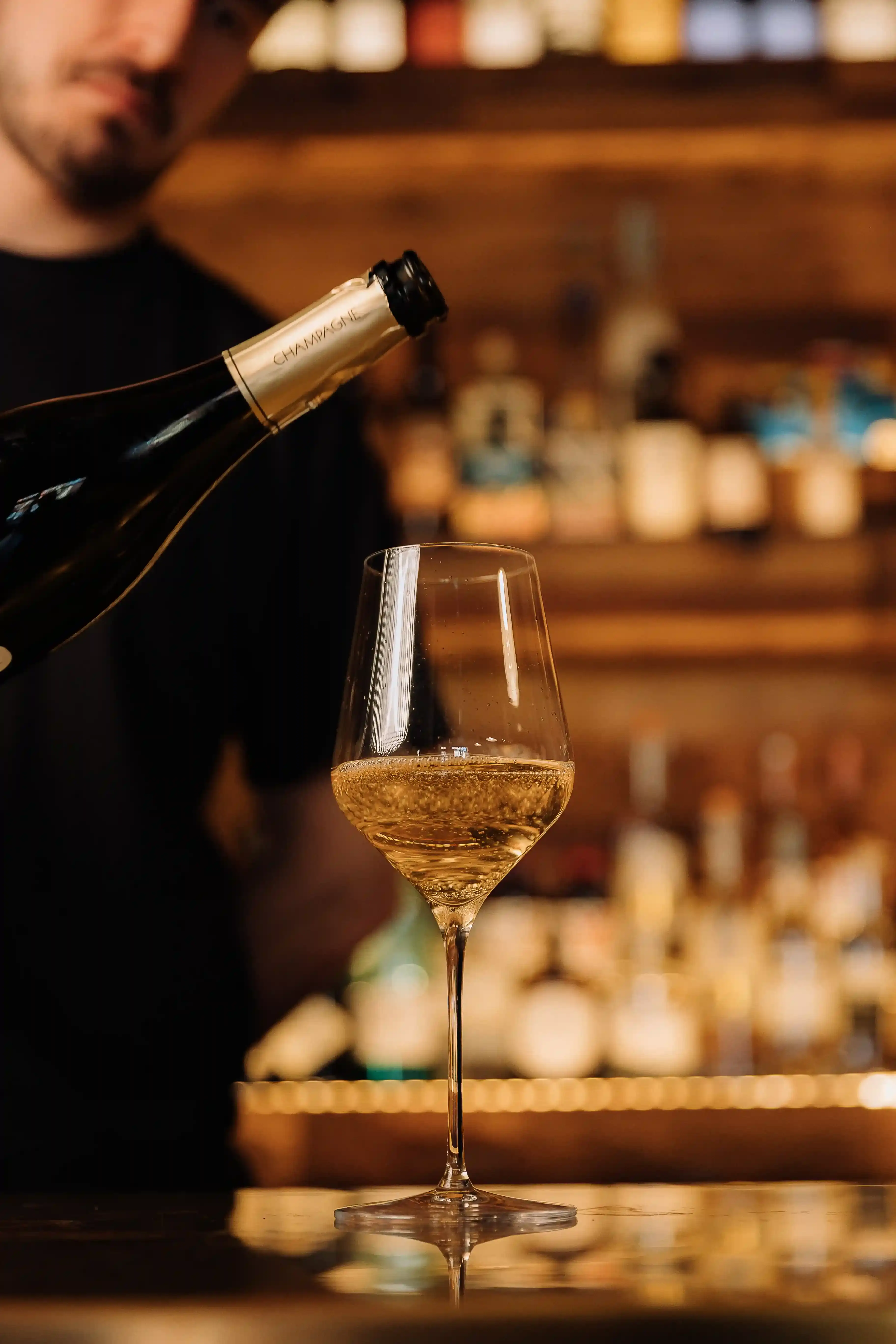 Un calice di bollicine servito al banco dell'enoteca